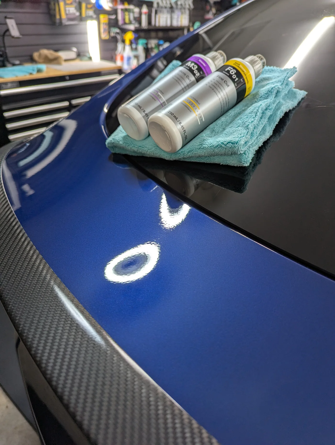 Ceramic coating products resting on a microfiber towel on a blue vehicle