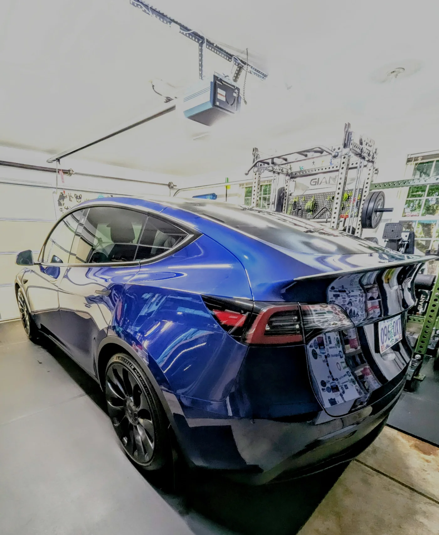 Rear three-quarter view of a glossy blue vehicle inside the garage
