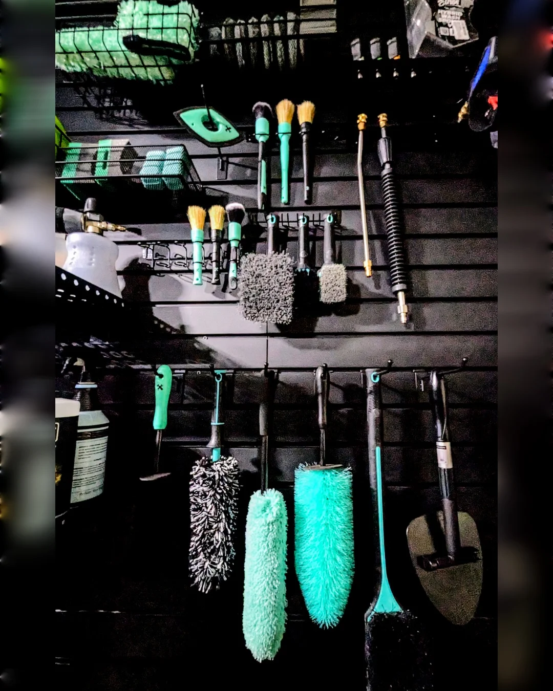 Detailing brushes, wash mitts, and tools organized on the studio wall